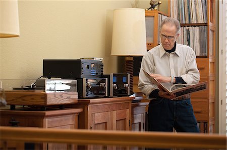 simsearch:649-07437113,k - Senior man reading vinyl record cover in living room Foto de stock - Royalty Free Premium, Número: 614-08030670