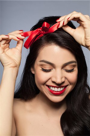 simsearch:693-03782738,k - Mid adult woman tying red ribbon in hair Foto de stock - Sin royalties Premium, Código: 614-08030695