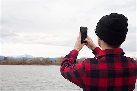 Mid adult man holding smart phone, taking photograph of view, rear view Stock Photo - Premium Royalty-Free, Code: 614-08030787