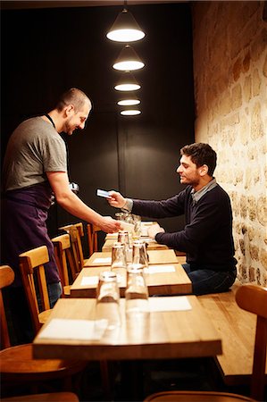 Man paying his bill in restaurant, using credit card Photographie de stock - Premium Libres de Droits, Code: 614-08030799