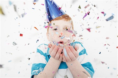 Boy wearing cone party hat blowing confetti Photographie de stock - Premium Libres de Droits, Code: 614-08030840