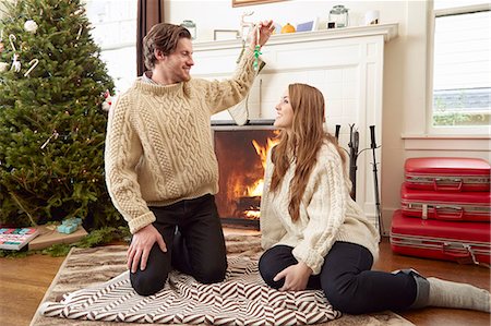 simsearch:649-08949589,k - Young couple sitting on living room rug holding up christmas decoration Photographie de stock - Premium Libres de Droits, Code: 614-08030900