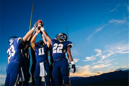 energetic collaboration - Teenage and young male american football team celebrating and holding up ball Stock Photo - Premium Royalty-Free, Code: 614-08030968