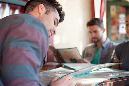 Three friends looking at menus in vegetarian restaurant Photographie de stock - Premium Libres de Droits, Code: 614-08031001