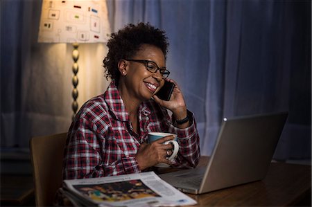 Mature woman on smartphone using laptop at home Stock Photo - Premium Royalty-Free, Code: 614-08031038