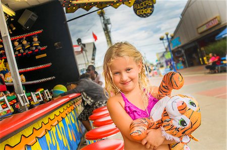 fun animals - Portrait of girl carrying prize tiger toy at fairground stall Stock Photo - Premium Royalty-Free, Code: 614-08031056