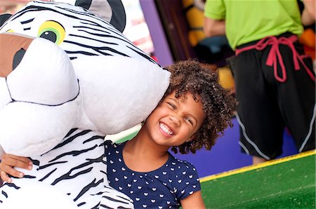 Portrait of girl in front of amusement stall carrying large prize tiger toy Photographie de stock - Premium Libres de Droits, Code: 614-08031070