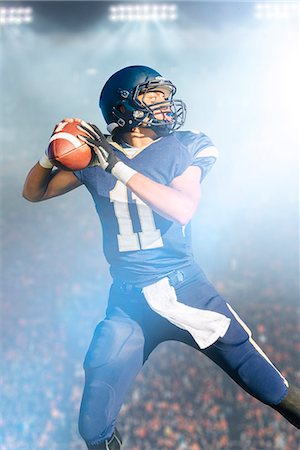 Teenage American football player jumping with ball Stock Photo - Premium Royalty-Free, Code: 614-08031089