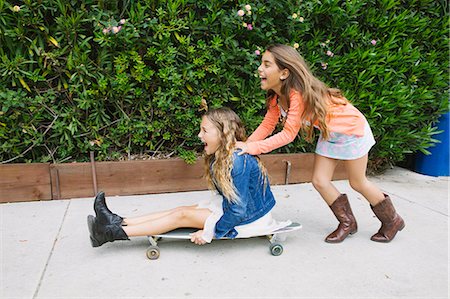 pushing - Girl pushing friend on skateboard Stock Photo - Premium Royalty-Free, Code: 614-08031166