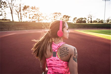 Rear view of young tattooed female athlete running on race track Foto de stock - Sin royalties Premium, Código: 614-08065911