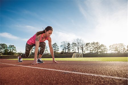 picture of lady at the start line in track - Young female athlete on her marks at race start line Stock Photo - Premium Royalty-Free, Code: 614-08065913