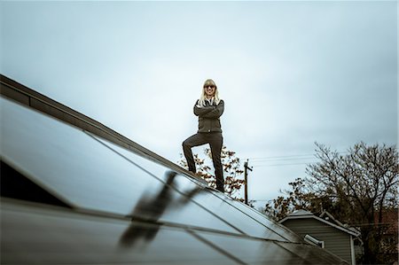 exterior home improvement - Portrait of mid adult woman standing on newly solar paneled house roof Stock Photo - Premium Royalty-Free, Code: 614-08065956