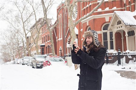 snow covered - Young man reading text on smartphone in snow covered street Photographie de stock - Premium Libres de Droits, Code: 614-08066030