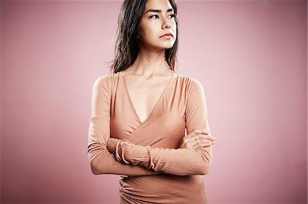 Portrait of young woman with arms crossed and serious expression Stock Photo - Premium Royalty-Free, Code: 614-08066055