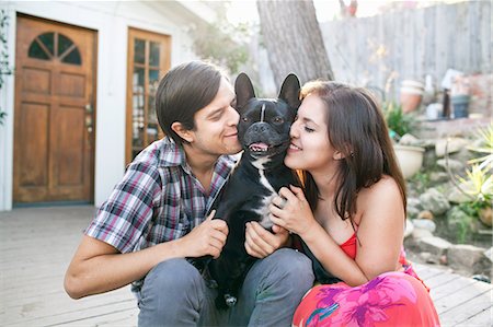 person with dog - Young couple sitting on patio snuggling up to dog Stock Photo - Premium Royalty-Free, Code: 614-08081242