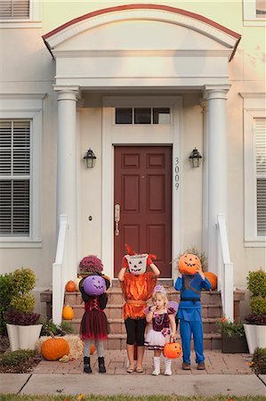 Children covering face with Jack O' Lantern bucket in front of house Photographie de stock - Premium Libres de Droits, Code: 614-08081271