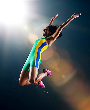 Young female athlete jumping mid air in celebration in stadium Stock Photo - Premium Royalty-Free, Code: 614-08081435