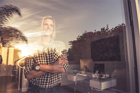 Portrait of young woman watching sunset from suburban window Stock Photo - Premium Royalty-Free, Code: 614-08081431