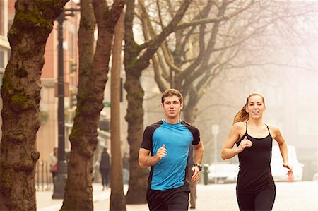 person jogging in city - Young man and woman running along misty tree lined street, Pioneer Square, Seattle, USA Stock Photo - Premium Royalty-Free, Code: 614-08081455