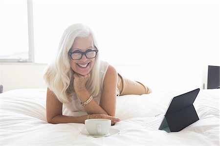 Senior woman lying on bed, with tablet computer and cup of tea Foto de stock - Sin royalties Premium, Código: 614-08081460