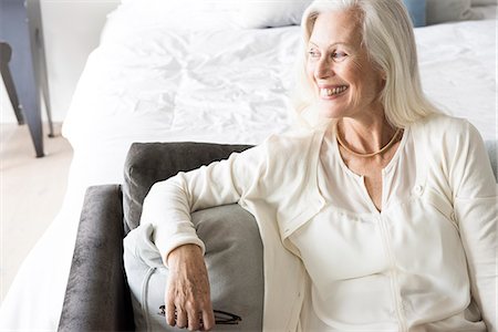 Senior woman sitting on sofa, looking away Stock Photo - Premium Royalty-Free, Code: 614-08081463