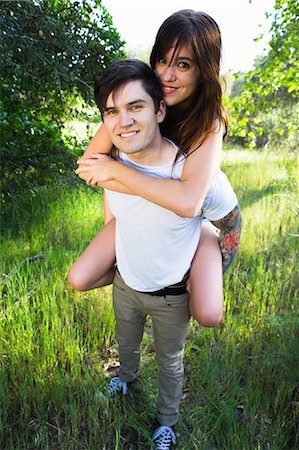 simsearch:649-08179955,k - Young man giving girlfriend piggyback ride in park Fotografie stock - Premium Royalty-Free, Codice: 614-08119477