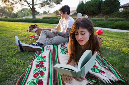 Young woman reading book whilst boyfriend pets dog in park Foto de stock - Sin royalties Premium, Código: 614-08119485