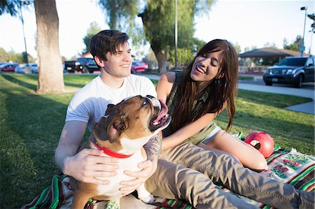 pets and owners - Young couple in park petting bulldog Stock Photo - Premium Royalty-Free, Code: 614-08119482