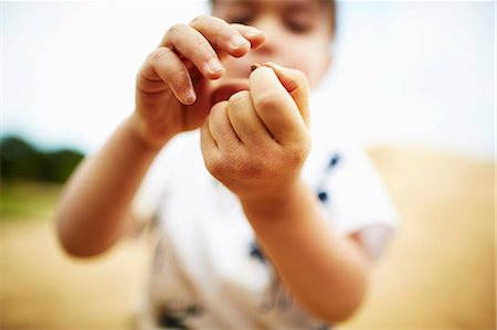 Close up of boy holding a pebble in his hands Photographie de stock - Premium Libres de Droits, Code: 614-08119532