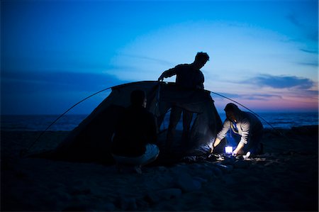 Group of friends setting up tent on beach at sunset Stock Photo - Premium Royalty-Free, Code: 614-08119615
