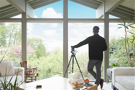 Rear view of man leaning on telescope looking out of window admiring garden scenic Foto de stock - Sin royalties Premium, Código: 614-08119689