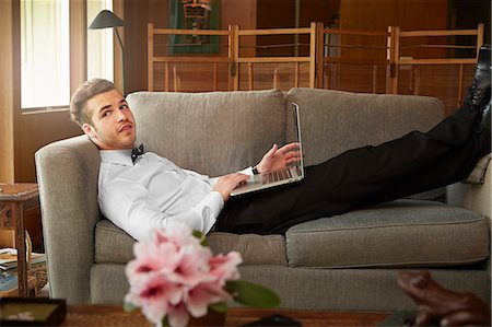 people home comfort adult - Portrait of man wearing smart clothes laying on sofa using laptop Stock Photo - Premium Royalty-Free, Code: 614-08119696