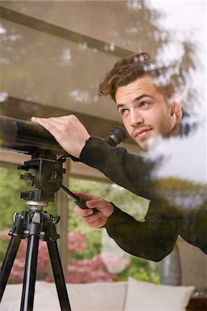 Portrait of man using telescope looking out of window Photographie de stock - Premium Libres de Droits, Code: 614-08119690