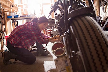 repair shop - Female mechanic working on motorcycle in workshop Stock Photo - Premium Royalty-Free, Code: 614-08126572