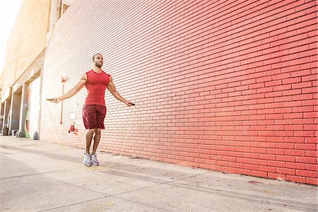 Male runner skipping on sidewalk Stock Photo - Premium Royalty-Free, Code: 614-08126727