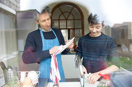 sweaters - View through window of teenage boy and father washing up in kitchen Stock Photo - Premium Royalty-Free, Code: 614-08126752