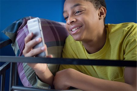 Close up of teenage boy lying in bunkbed reading smartphone text Foto de stock - Sin royalties Premium, Código: 614-08126787