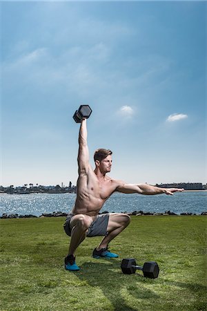 squats dumbbells - Mid adult man crouching and lifting dumb bells at coast Stock Photo - Premium Royalty-Free, Code: 614-08126807