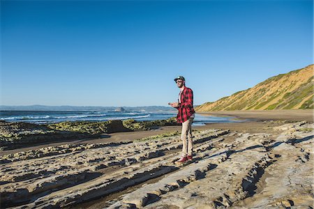 simsearch:614-06973887,k - Young man standing on beach looking at ocean Stock Photo - Premium Royalty-Free, Code: 614-08126874
