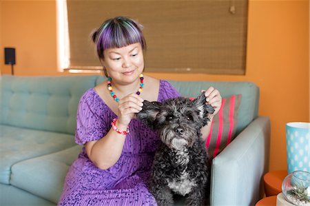 simsearch:614-03697070,k - Mid adult woman sitting on sofa with dog, holding dog's ears Fotografie stock - Premium Royalty-Free, Codice: 614-08148312