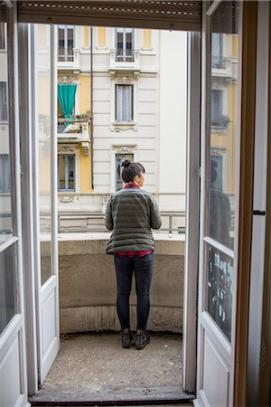 simsearch:614-08148474,k - Rear view through doorway of woman standing on balcony, Milan, Italy Fotografie stock - Premium Royalty-Free, Codice: 614-08148473