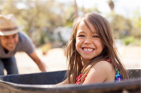family with two children - Portrait of girl in community garden riding in wheelbarrow Stock Photo - Premium Royalty-Free, Code: 614-08148585