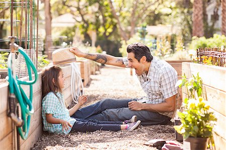 simsearch:614-08148597,k - Mid adult man  putting fedora on daughter in community garden Photographie de stock - Premium Libres de Droits, Code: 614-08148599