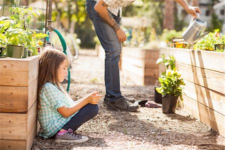 simsearch:614-08148597,k - Girl crouching in community garden using smartphone Photographie de stock - Premium Libres de Droits, Code: 614-08148600