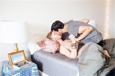 romantic home - Male couple on bed, holding hands, kissing Stock Photo - Premium Royalty-Free, Code: 614-08148669