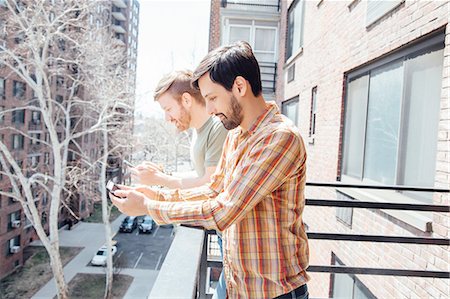 simsearch:614-08535703,k - Male couple standing on balcony, looking at smartphones Stock Photo - Premium Royalty-Free, Code: 614-08148676