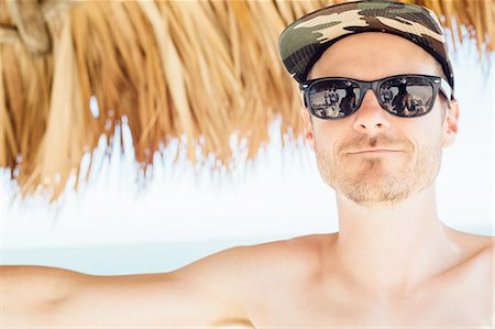 Portrait of mid adult man under cabana, wearing cap and sunglasses, Miami Beach, Florida, USA Stock Photo - Premium Royalty-Free, Code: 614-08148696