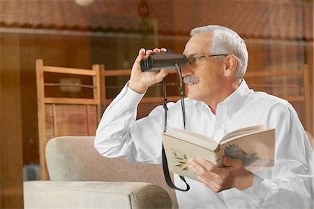 Senior man at home, birdwatching through window, using binoculars Stock Photo - Premium Royalty-Free, Code: 614-08202027