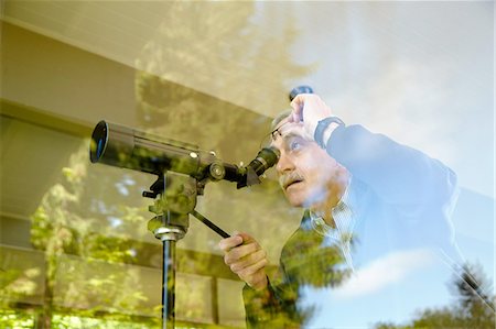 person focusing telescope - Senior man at home, using telescope through window Stock Photo - Premium Royalty-Free, Code: 614-08202034