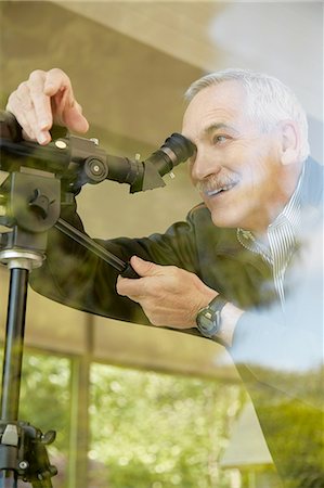 person focusing telescope - Senior man at home, using telescope through window Stock Photo - Premium Royalty-Free, Code: 614-08202032